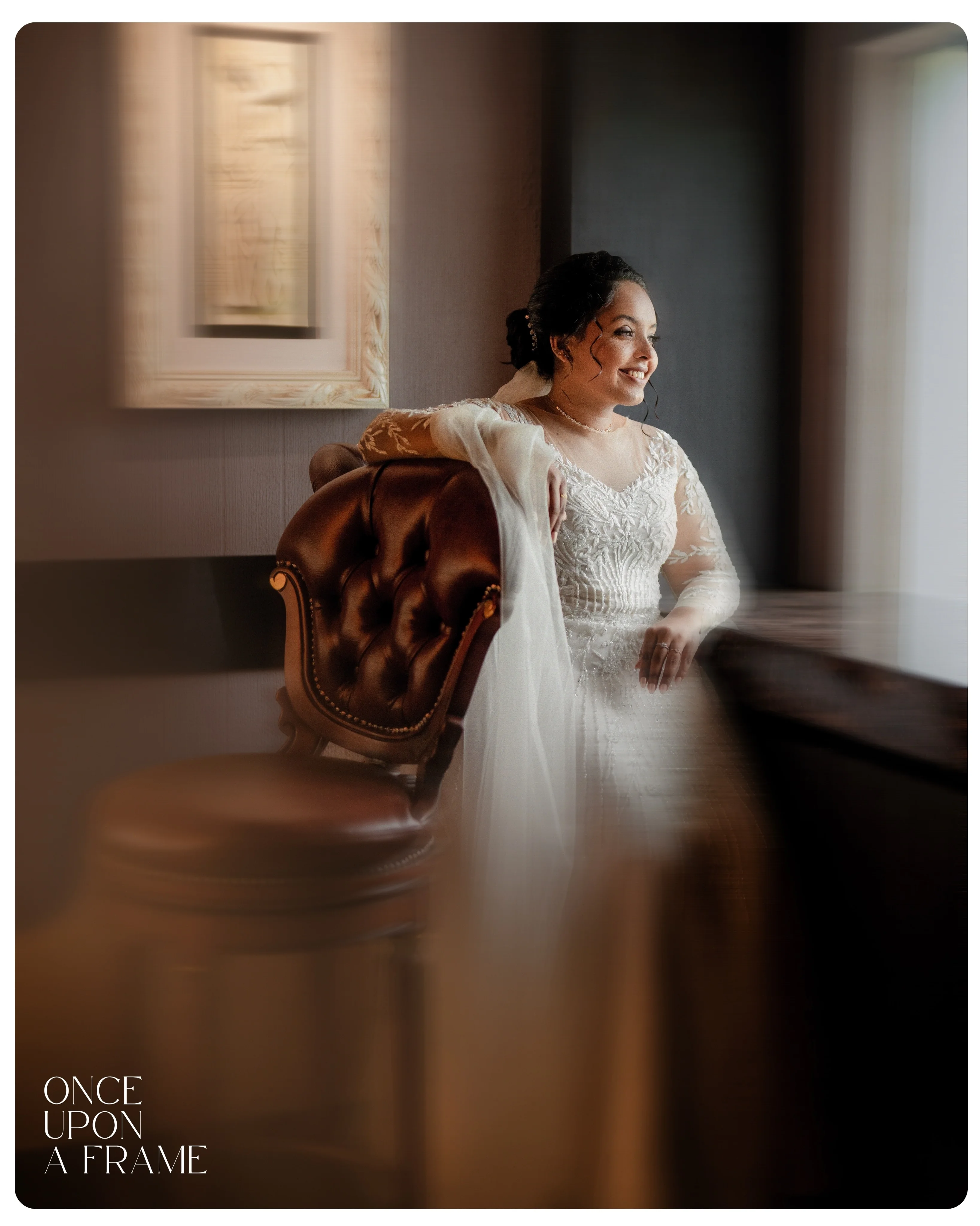 A bride smiling beside a window in warm natural light